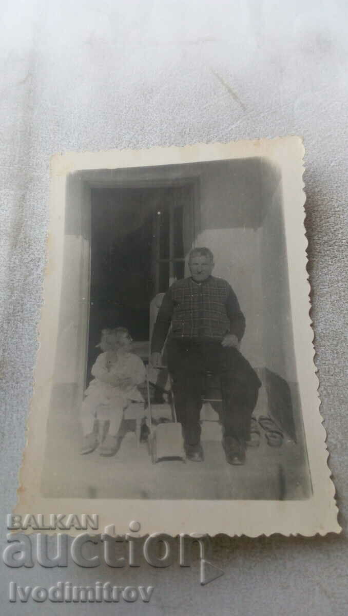 Φωτογραφία Ένας ηλικιωμένος άνδρας και ένα κοριτσάκι στις σκάλες μπροστά από το σπίτι