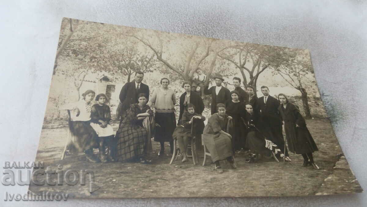 Fotografie Bărbați, femei și două fete pe scaune în curte 1923
