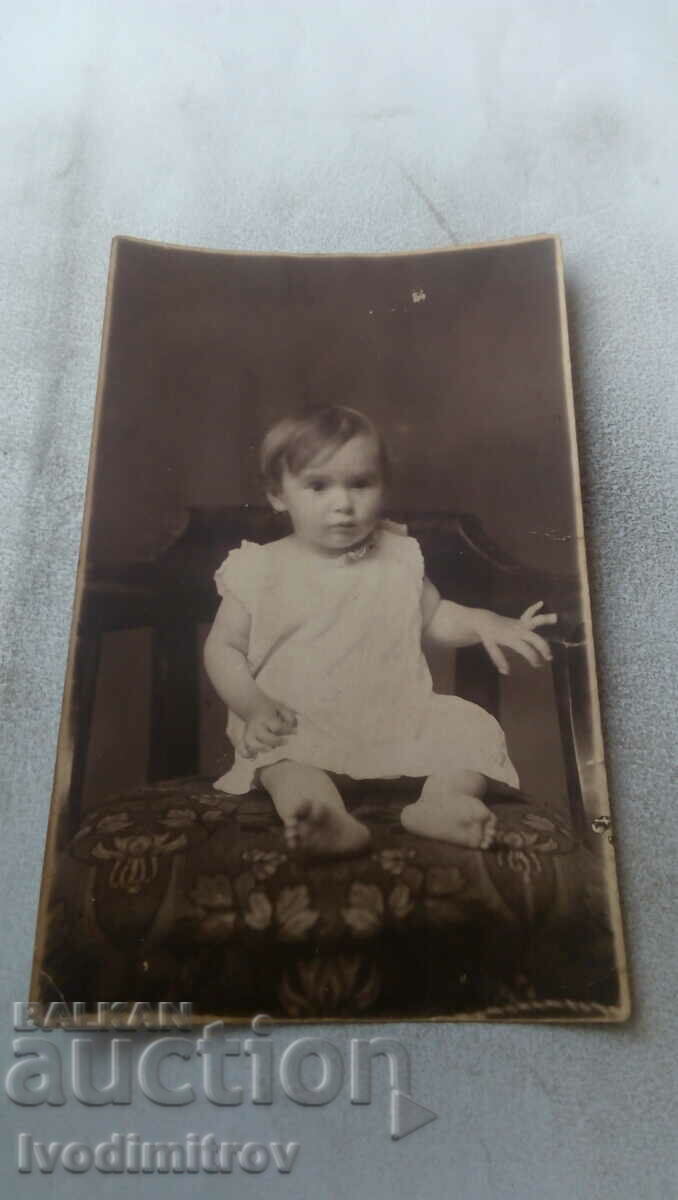 Снимка Малко момиченце с бяла рокличка върху стол