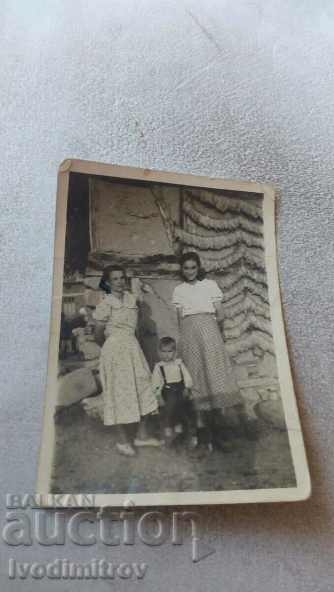 Снимка Две жени и малко момченце пред нанизи с тютюн