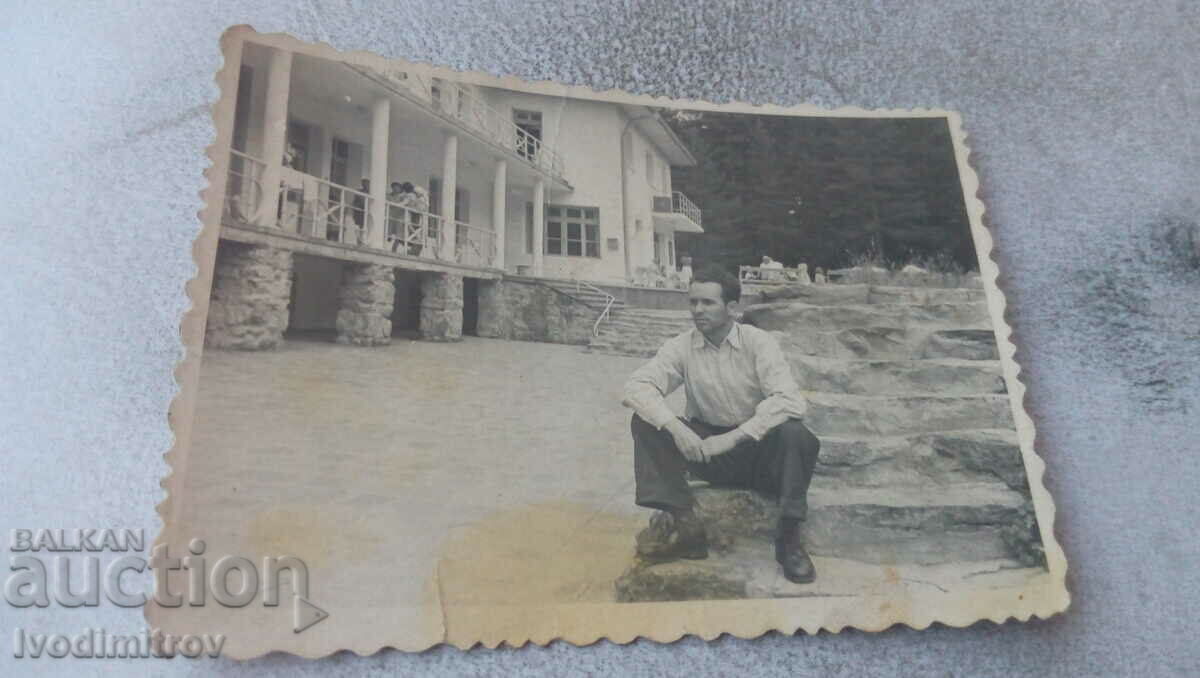 Φωτογραφία Ένας άνδρας που κάθεται στα σκαλοπάτια μπροστά από έναν σταθμό ανάπαυσης στα βουνά