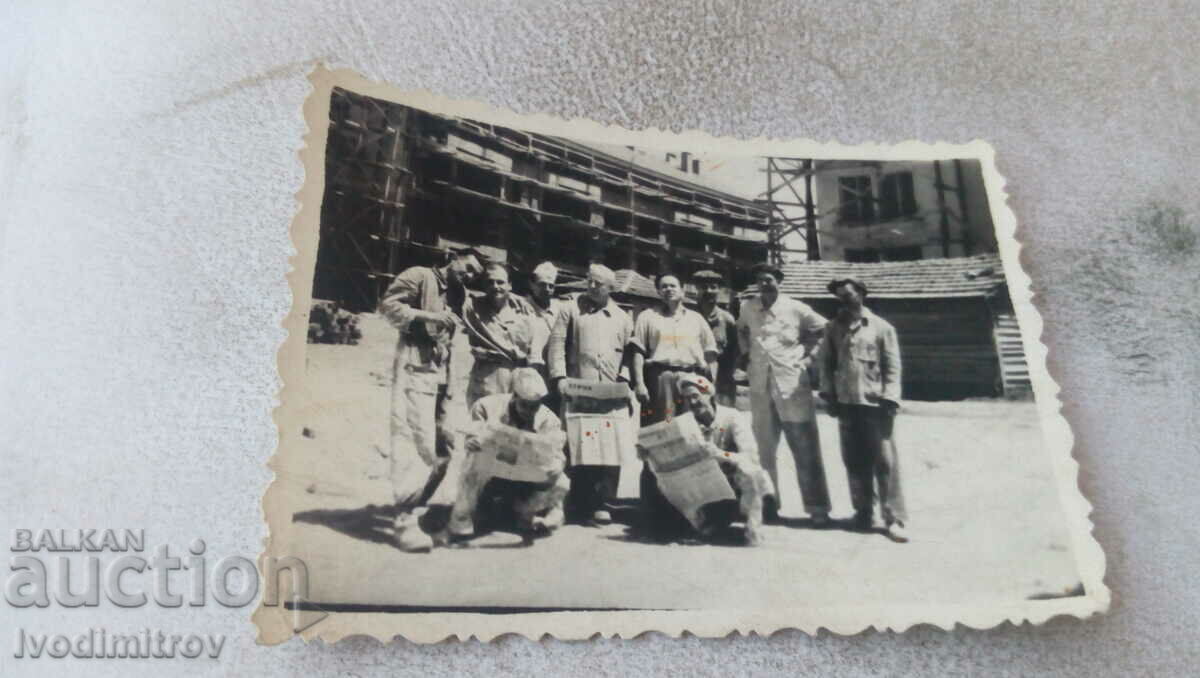 Photo Workers with newspapers Workers' case in front of construction