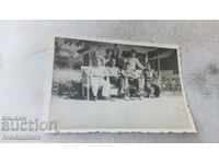 Photo Men and youths on wooden chairs in the yard