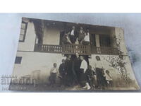 Fotografie Bărbați, femei și copii pe veranda unei case vechi