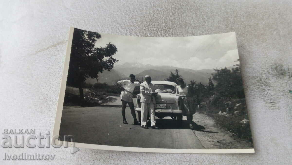 Photo Two men and a woman with a Moskvich car on the road
