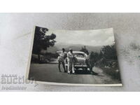 Foto Doi bărbați și o femeie cu o mașină Moskvich pe drum