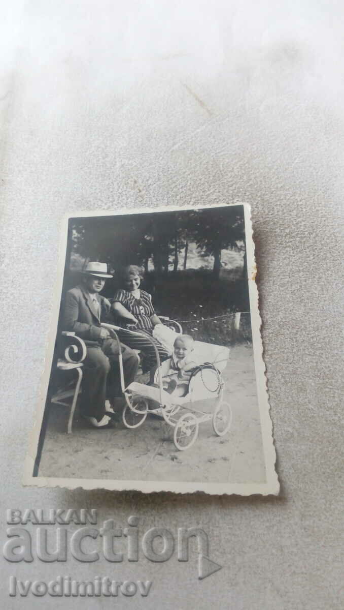 Photo Man woman and little boy with retro stroller in the park