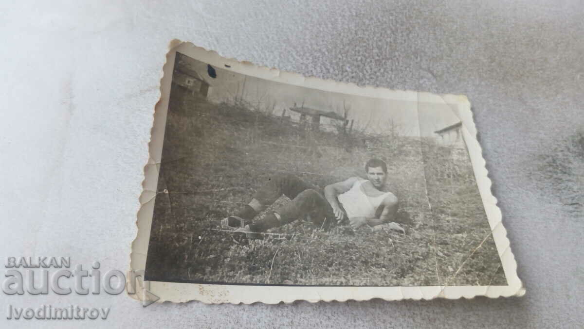Photo A man in a tank top lying on the grass