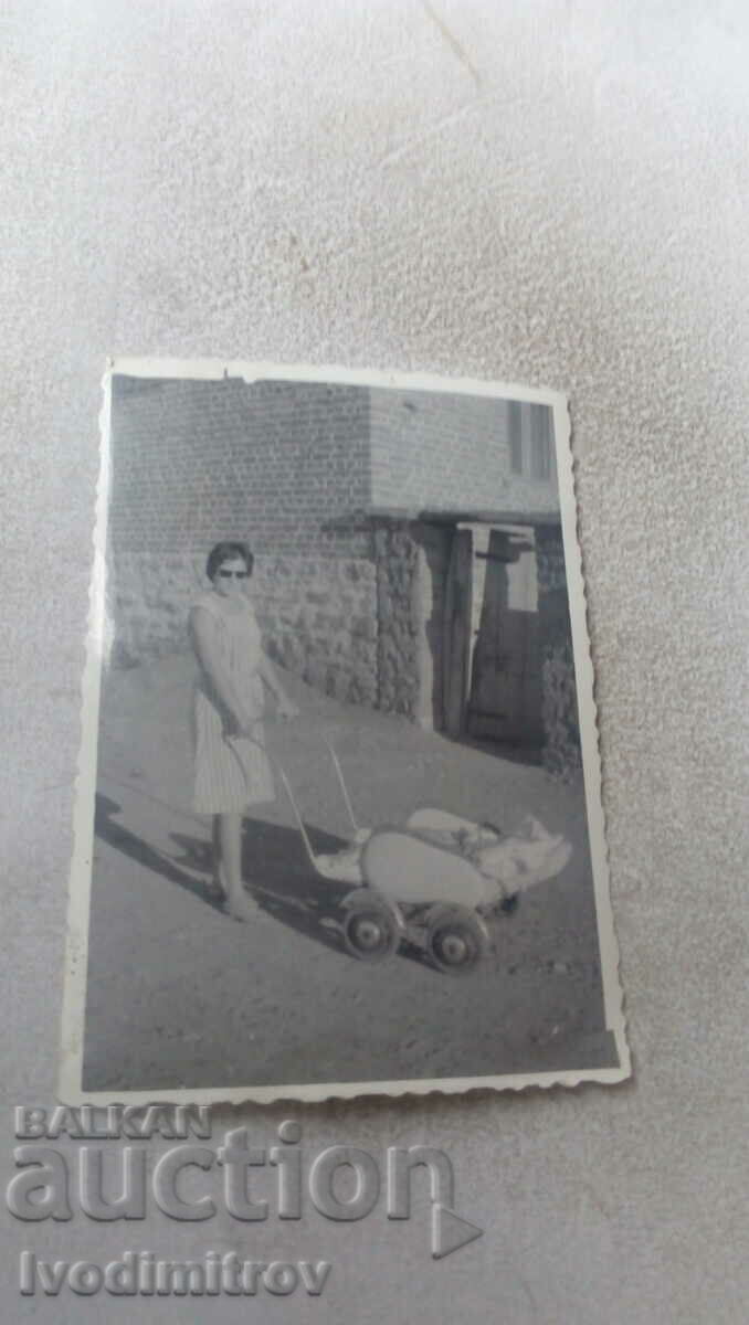 Fotografie cu o femeie cu un copil într-un cărucior de epocă pe stradă