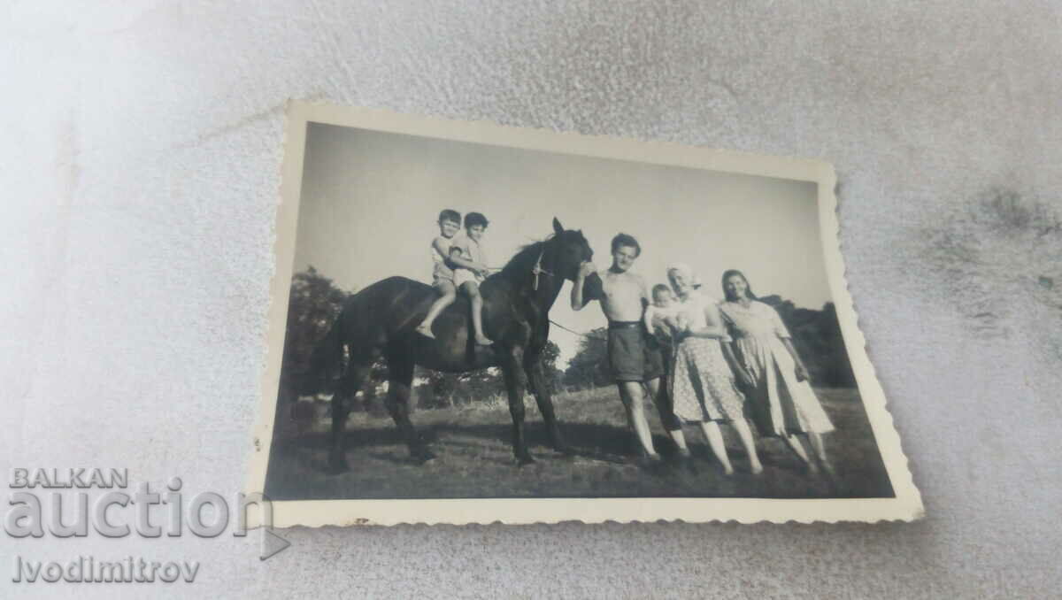 Свимка Двама мъже жени и деца с черен кон