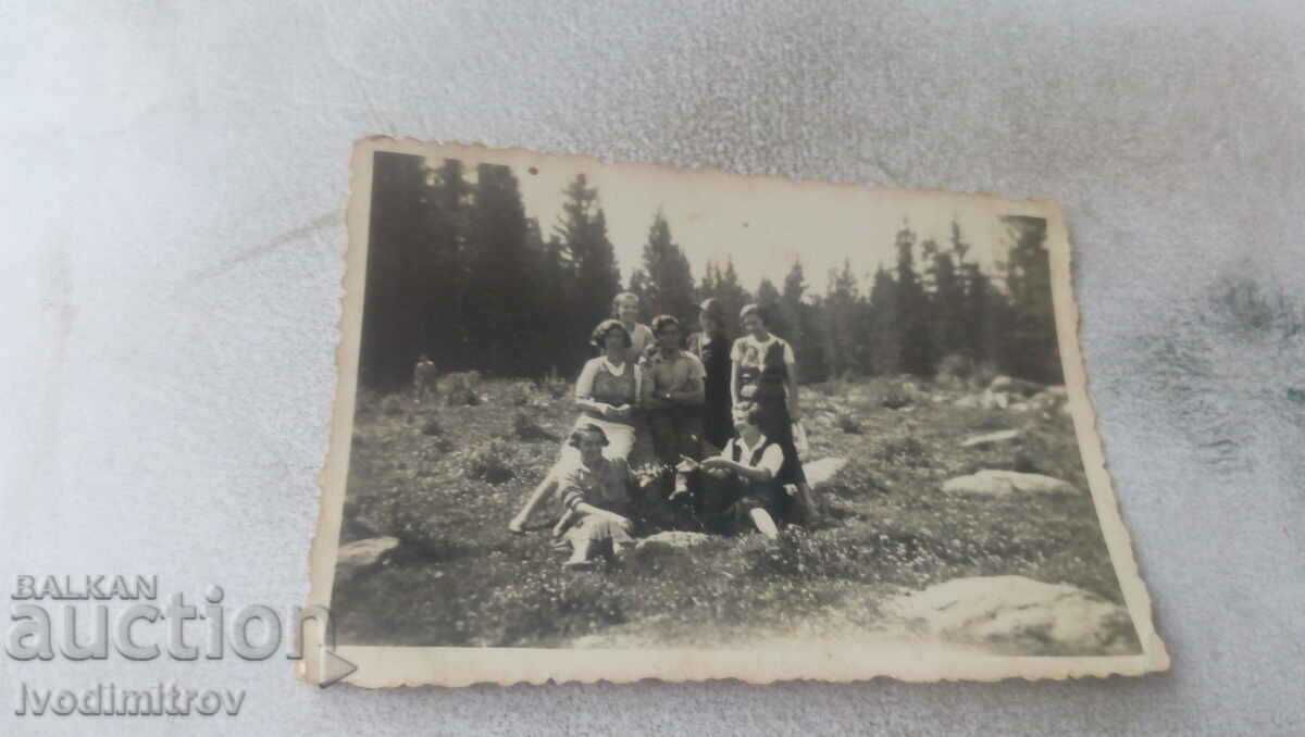 Photo Young man and girls on a meadow in the mountains