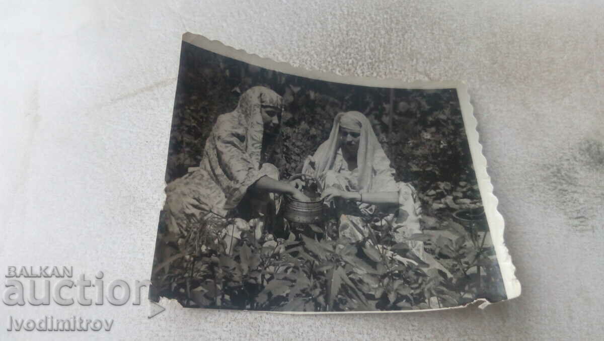 Photo Two young women with a copper bear in the garden