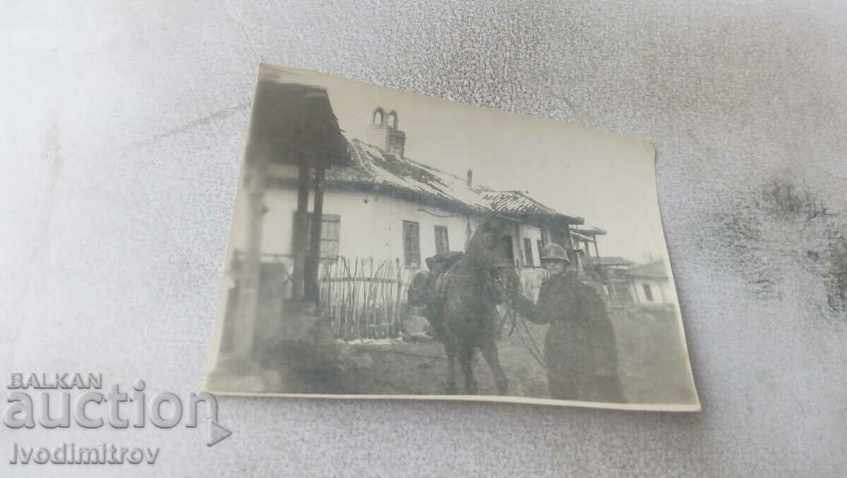 Φωτογραφία Ένας στρατιώτης με ένα άλογο μπροστά από ένα εξοχικό σπίτι