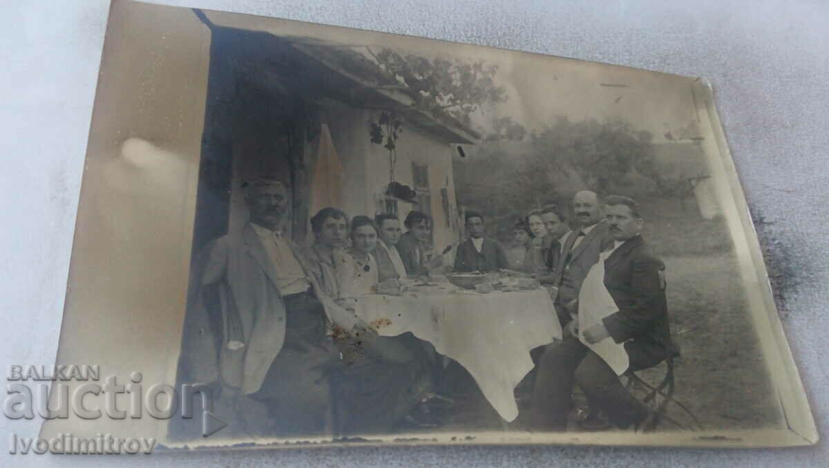 Foto Bărbați și femei în jurul unei mese în curte