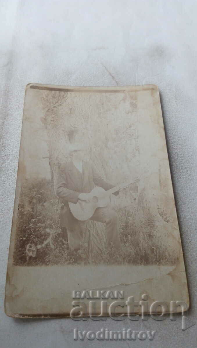 Снимка Мъж с китара до дърво