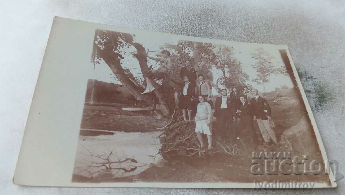 Φωτογραφία Νέοι άνδρες και γυναίκες σε ένα δέντρο δίπλα στο ποτάμι
