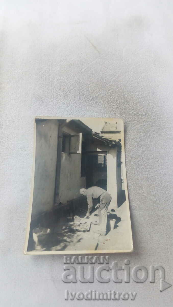 Fotografie Un bărbat repara gresie în fața casei sale