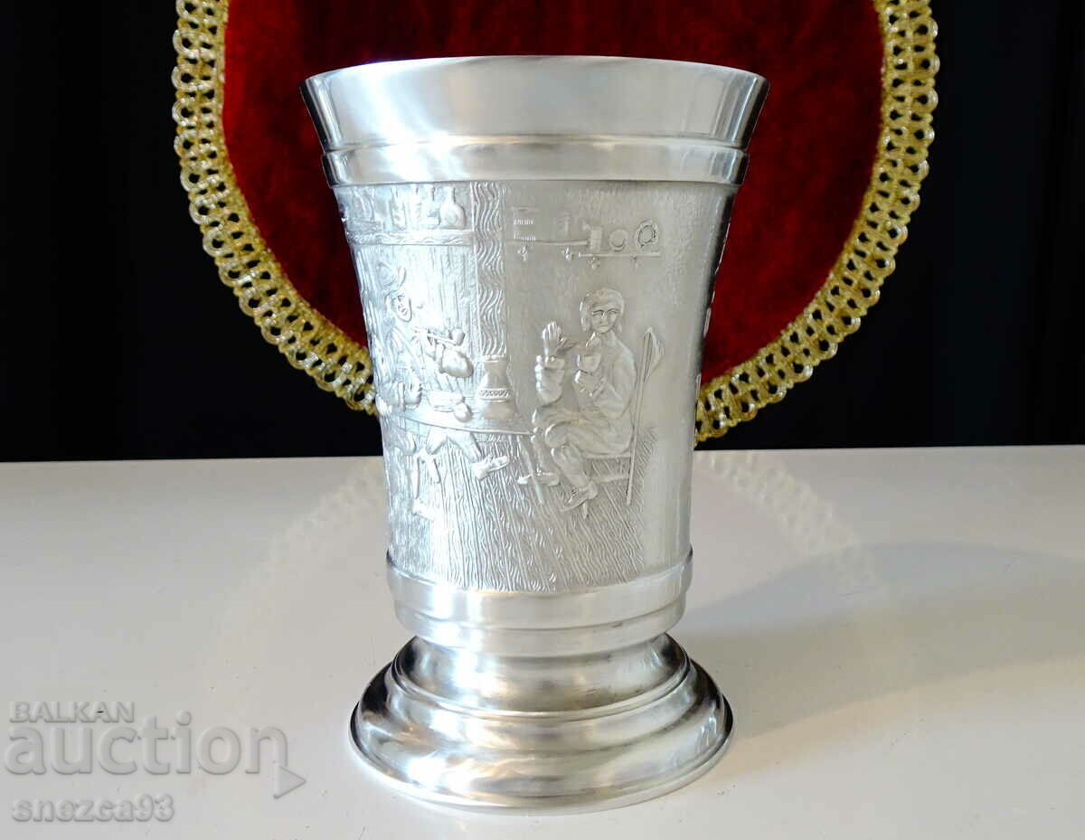 A mug, a pewter goblet with a painting Table. A mug, a pewter goblet with a painting Table.