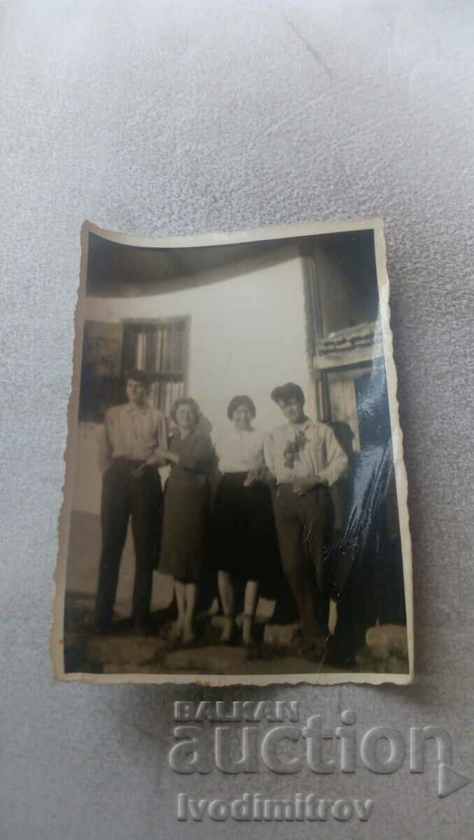 Photo Two men and two young women in front of a house