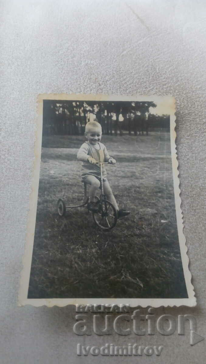 Φωτογραφία Ένα αγόρι με ένα παιδικό ρετρό ποδήλατο