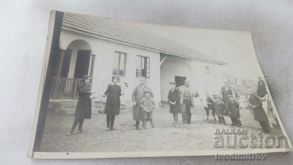 Foto Bărbați femei copii și două vaci în curte