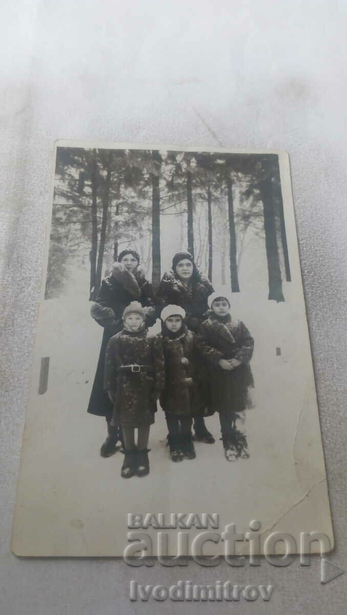 Φωτογραφία Δύο γυναίκες και τρία κορίτσια σε ένα πευκοδάσος το χειμώνα