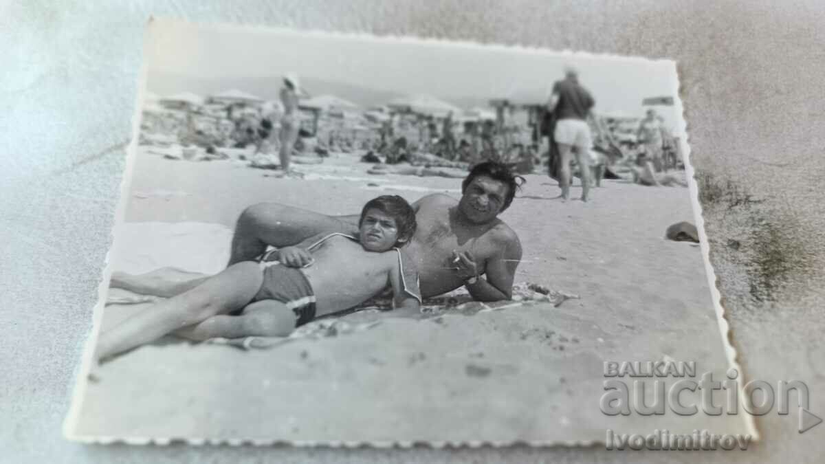 Fotografie cu un bărbat și un băiat pe plajă