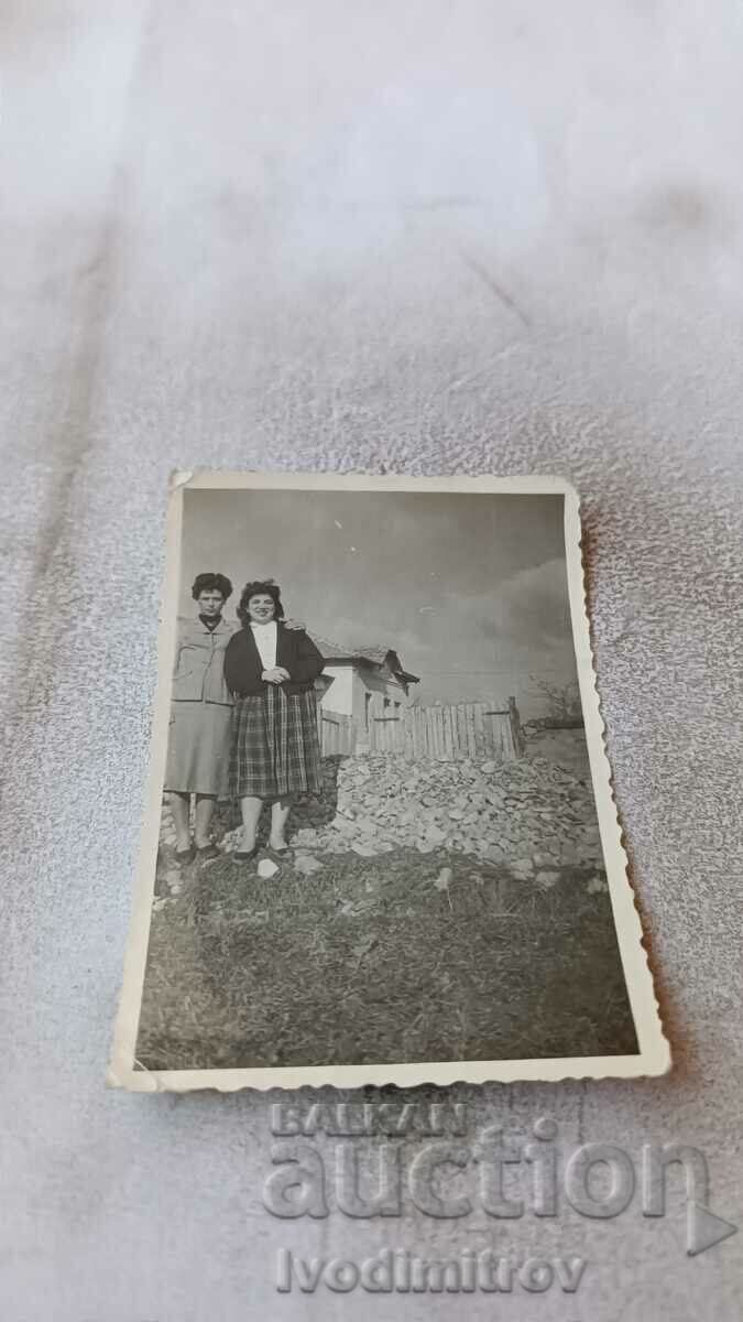Photo Two women by the fence of a house