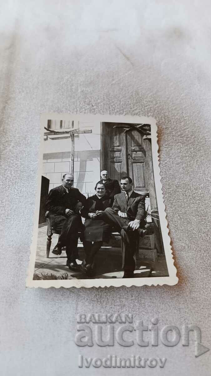 Foto Trei bărbați și o femeie în fața unei case