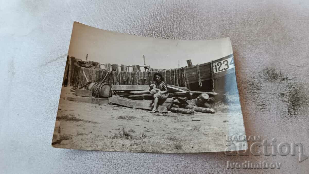 Снимка Жена седнала на купчина дърва в двора