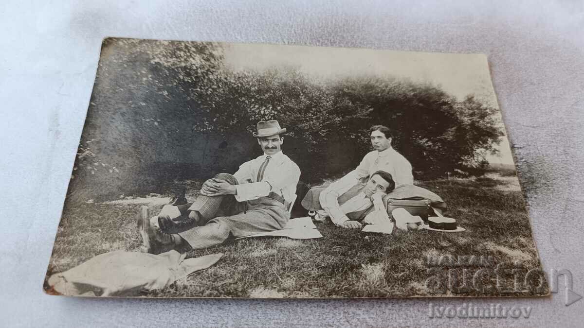 Photo Three men sitting on the grass in the park