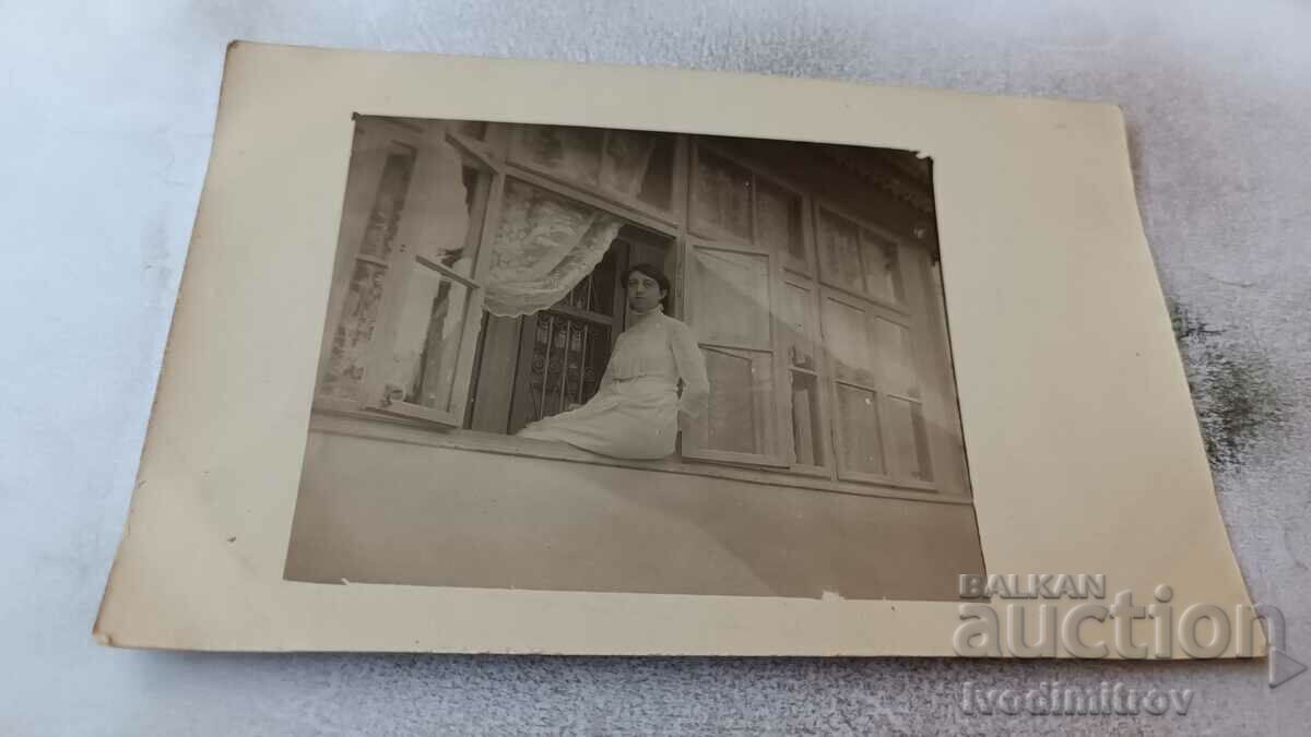 Φωτογραφία Νεαρή γυναίκα με λευκό φόρεμα σε περβάζι