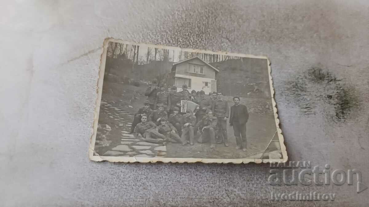 Photo Soldiers with an accordion in front of a mountain hut