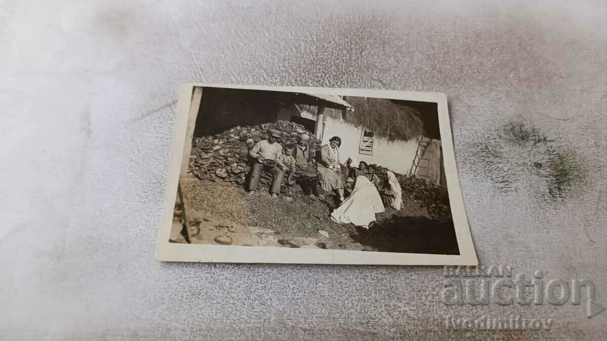 Fotografie Barbat femei si copii in curtea unei case vechi de tara