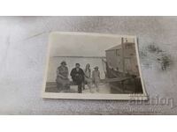 Φωτογραφία Ένας άνδρας και τρεις γυναίκες κάθονται σε μια σανίδα στο λιμάνι
