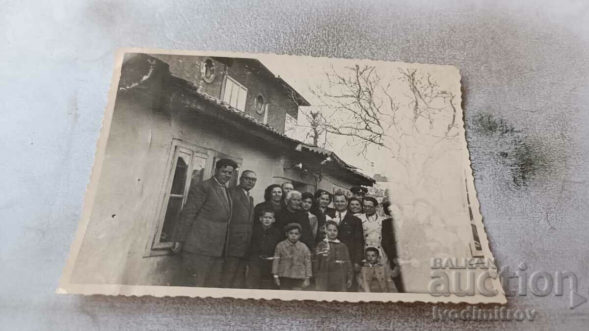 Photo Men women and children next to a house