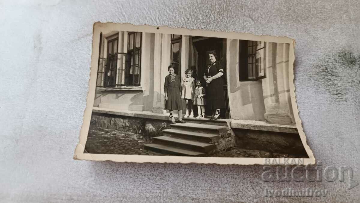 Photo Woman two girls and a boy on stairs in front of a house 1932