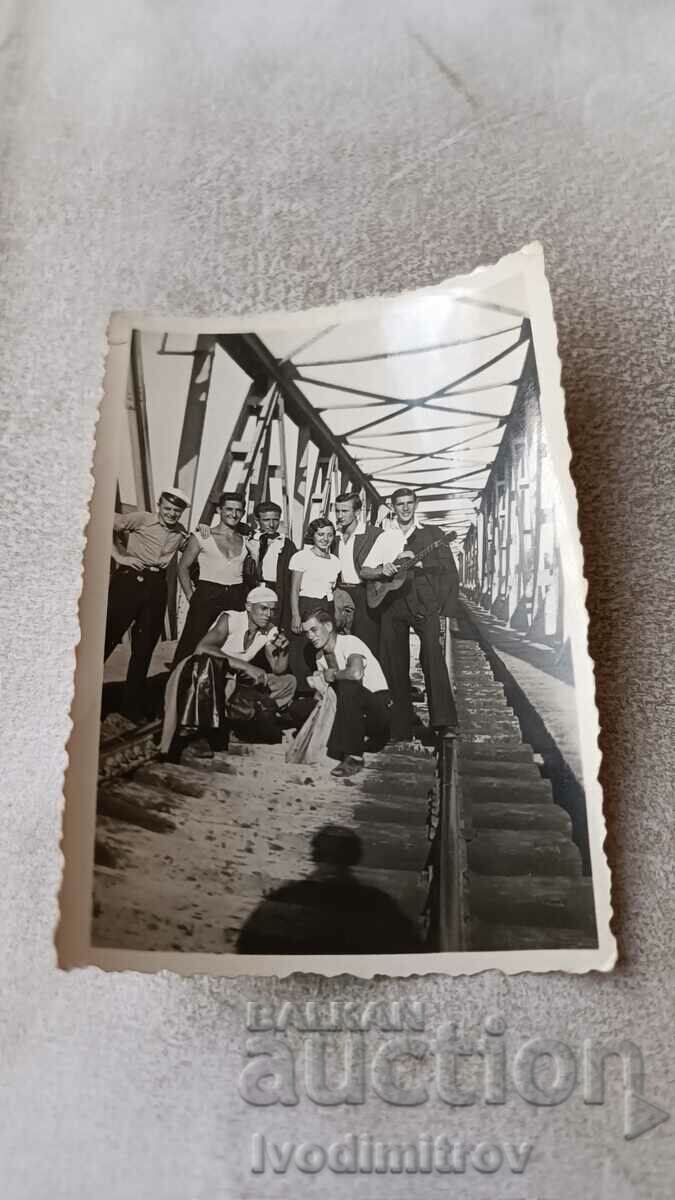 Photo Young girl and men with guitar on railway bridge
