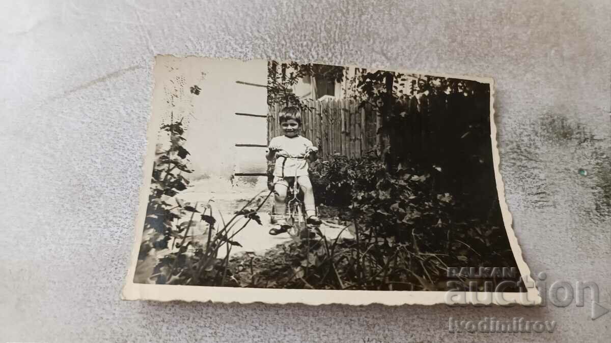Photo A little boy with a retro children's bicycle in the yard