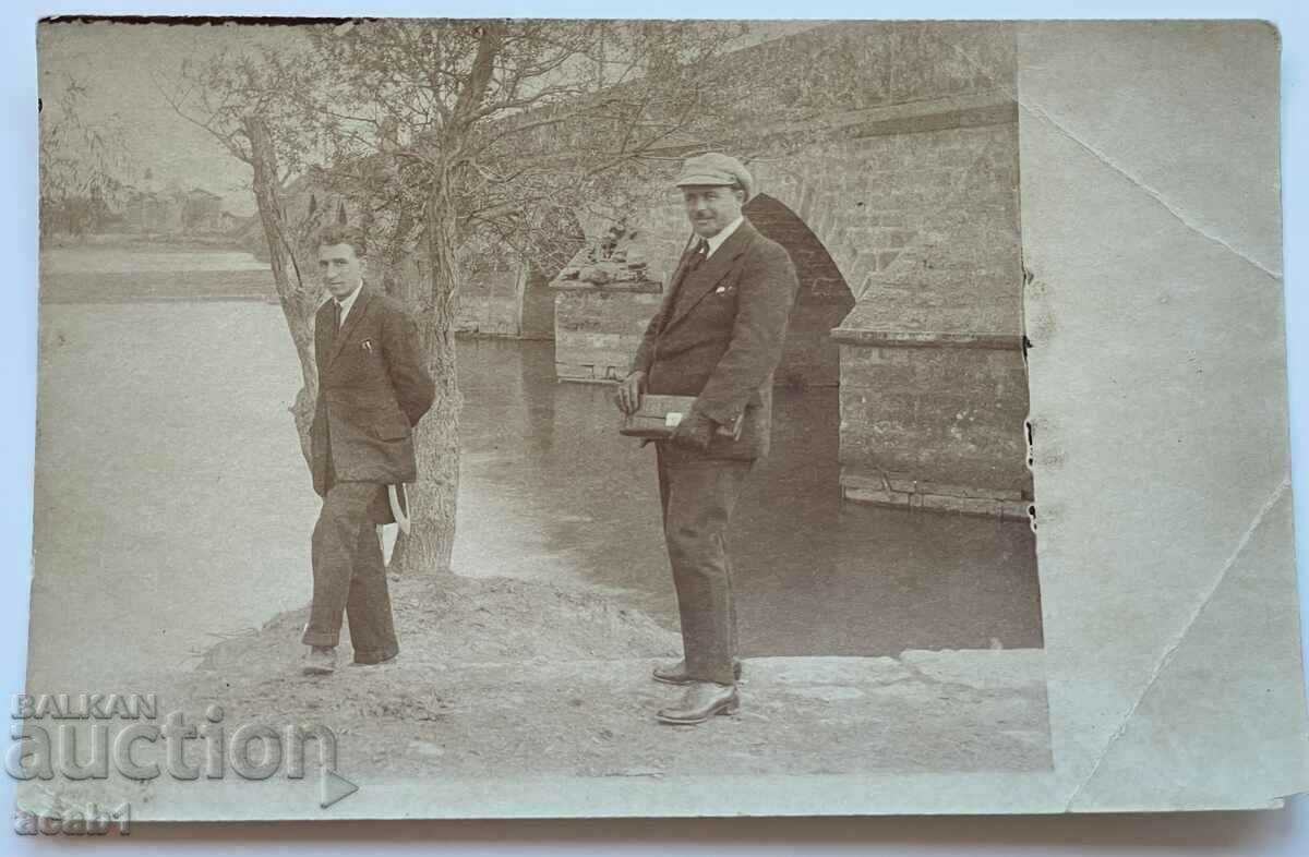 Gentlemen in front of a bridge