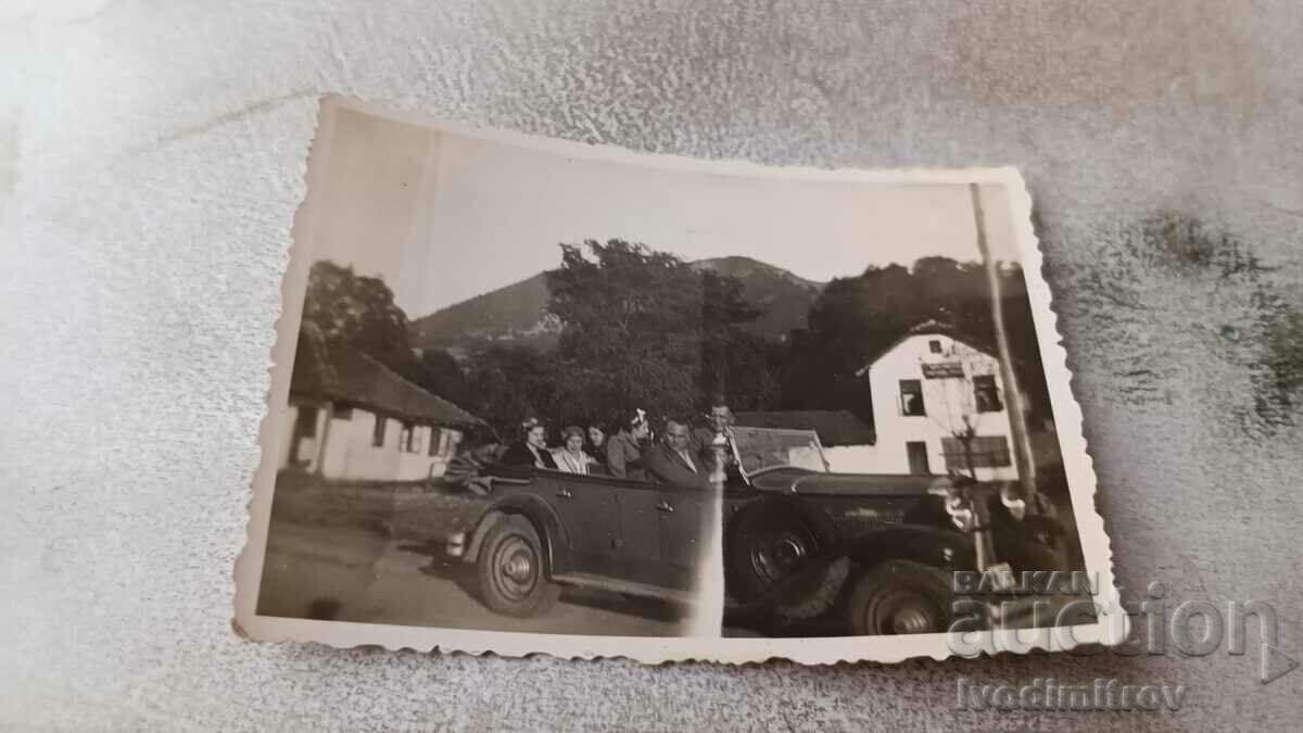 Foto Bărbați și femei cu o mașină retro