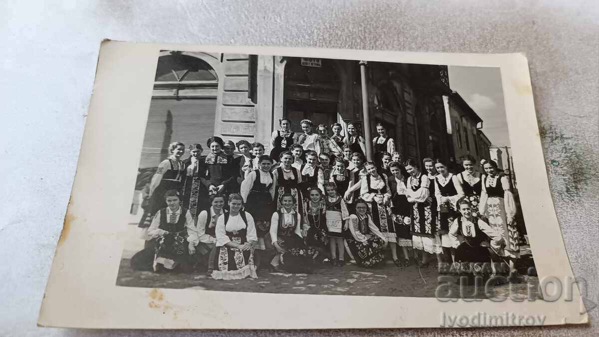 Η κα Νεαρά κορίτσια με λαϊκές φορεσιές μπροστά στη φωτογραφία Τσέκο Γ. Πέτροβα