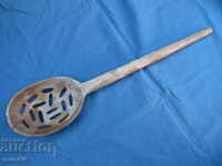 Large wooden slotted spoon of yellow cheese