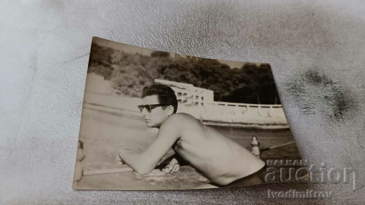 Photo A man in a swimsuit with sunglasses on the pier