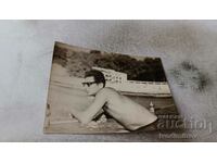 Fotografie Un bărbat în costum de baie cu ochelari de soare pe debarcader