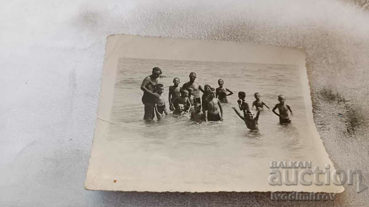 Foto Doi bărbați și copii pe plajă