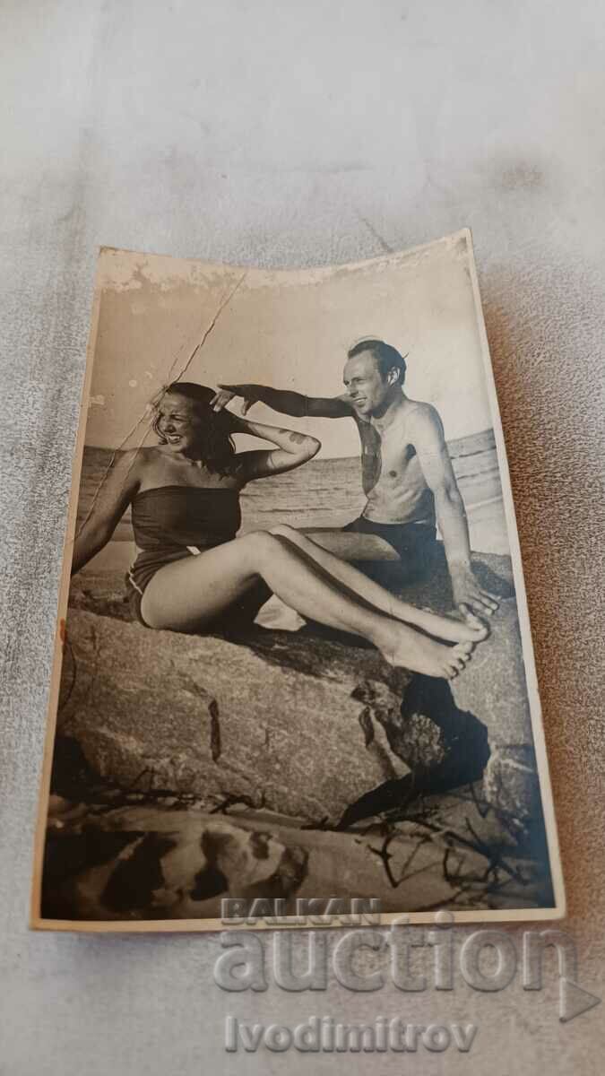Φωτογραφία Άνδρας και νεαρό κορίτσι σε έναν βράχο στην παραλία 1956