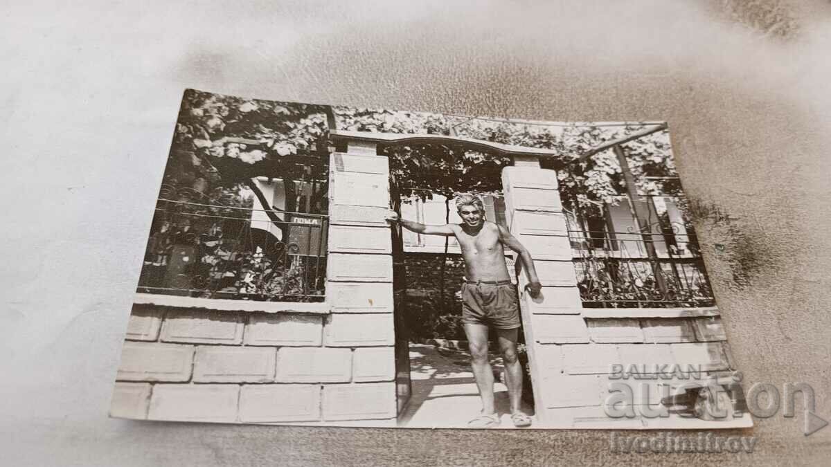 Photo A man in shorts at the front door to his yard
