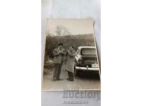 Photo Two men lighting cigarettes next to a vintage car 1955