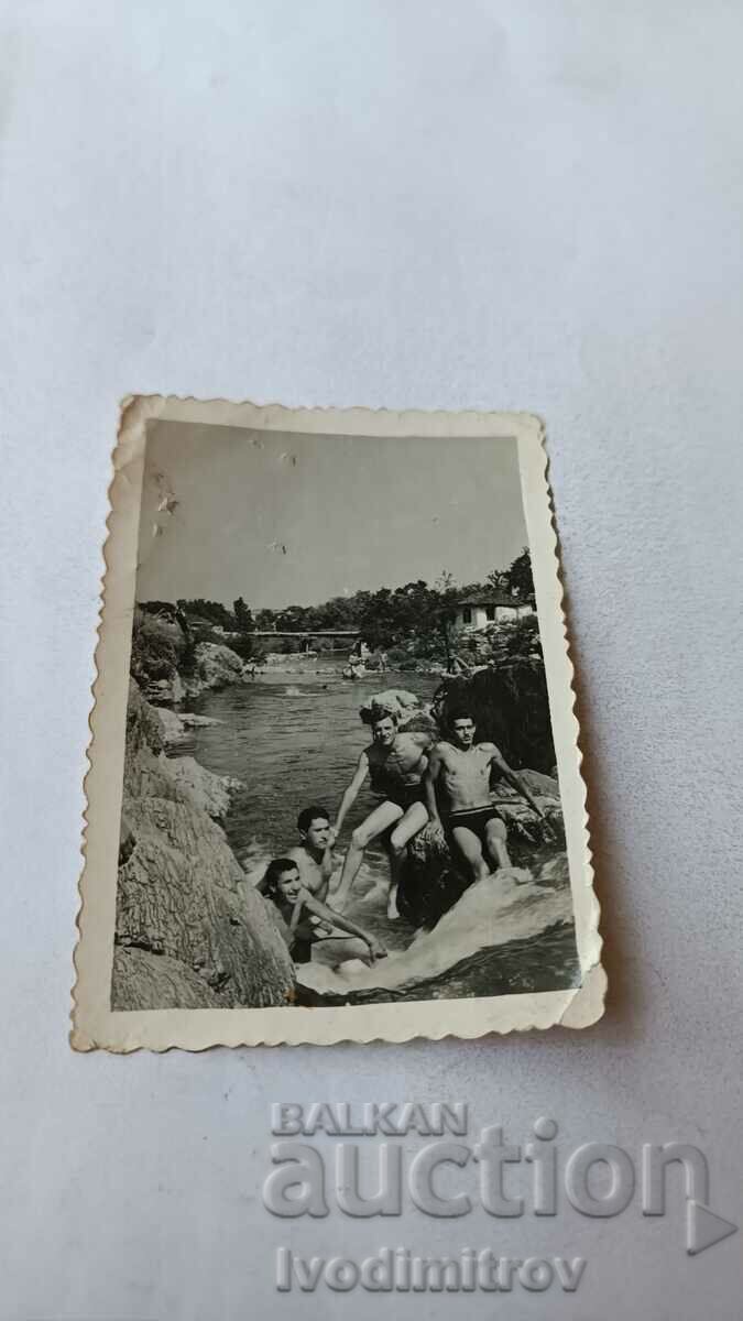 Photo Four young men in swimsuits in a pool of the river